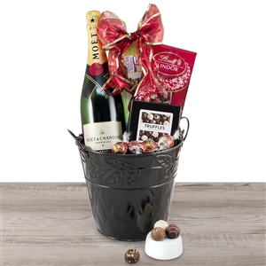 A bottle of Moet and Chandon Champagne and truffles elegantly presented in a black chiller