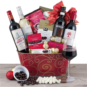 A red and gold oval metal basket with 4 bottles of wine and tons of Christmas treats.